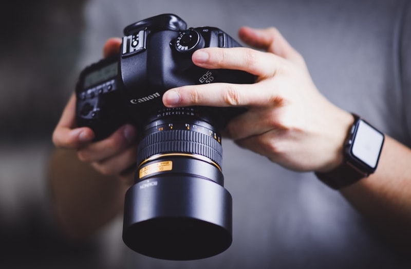 Photographer's hands adjusting the lens of a DSLR camera