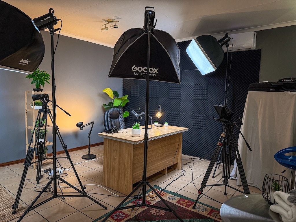 Wide view of the 3-Axis YouTube studio with softbox lights, presenter desk and teleprompter camera