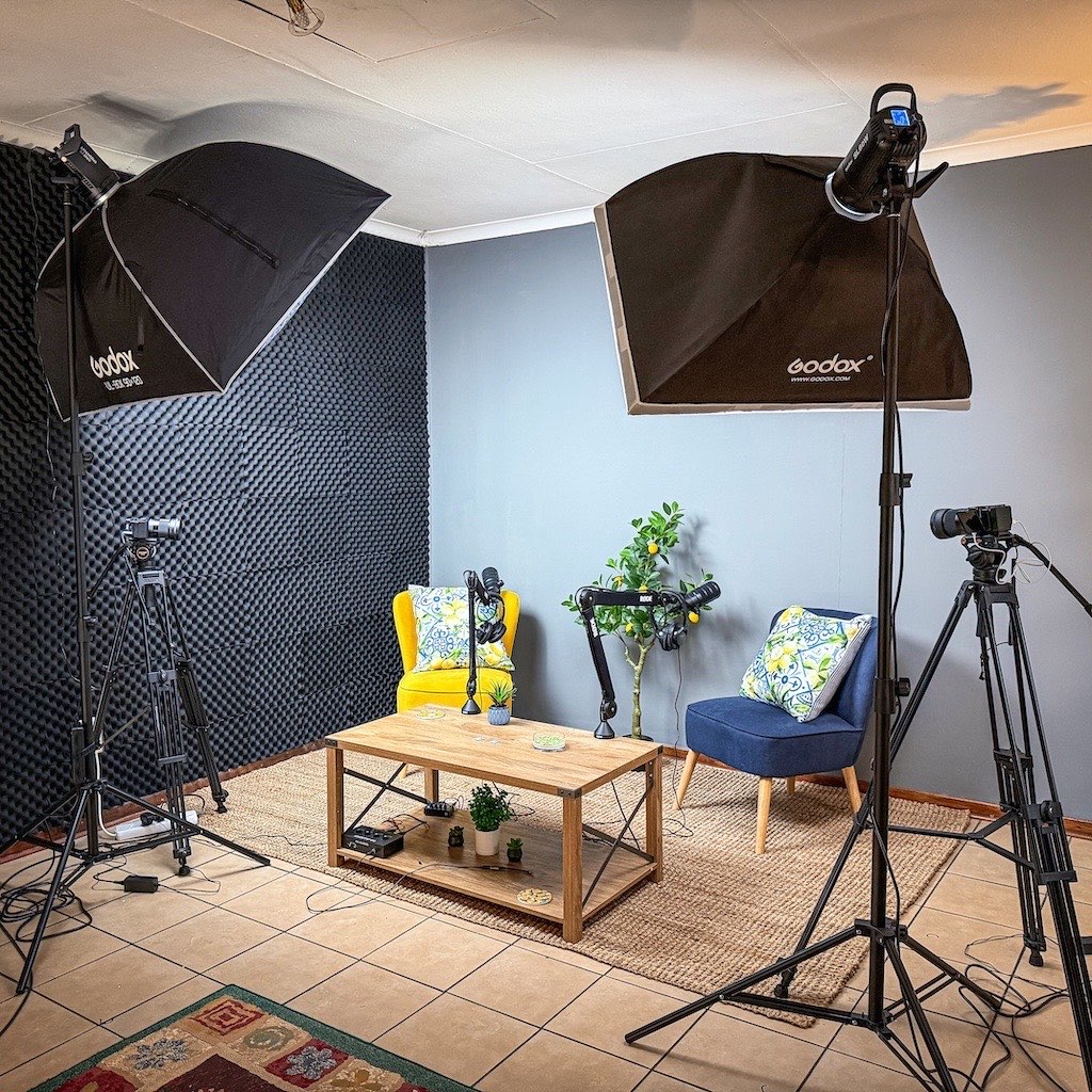 Podcast studio corner with two armchairs, RODE boom-arm microphones and softbox lighting